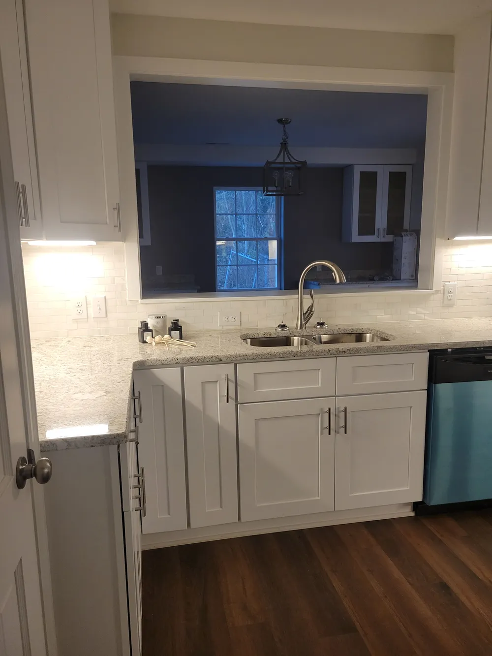 Kitchen sink and white cabinetry beside a pass-through