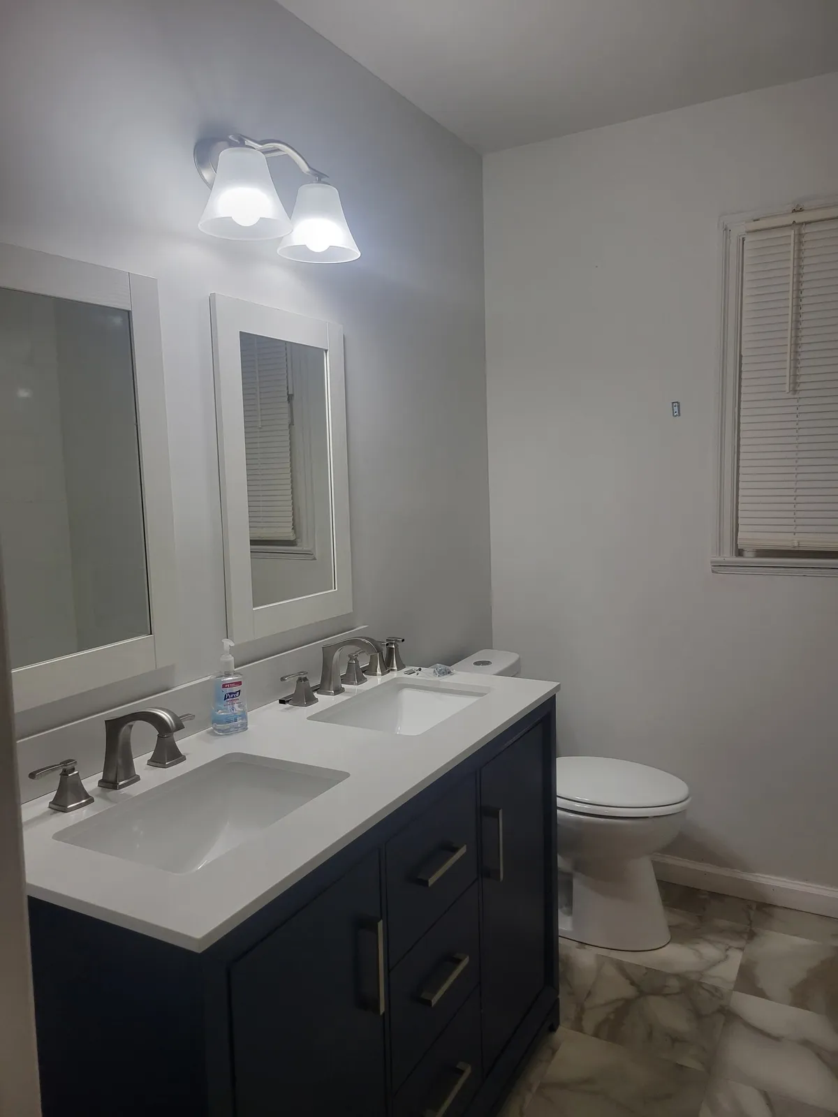 Bathroom with a navy double vanity, a white top and two framed mirrors