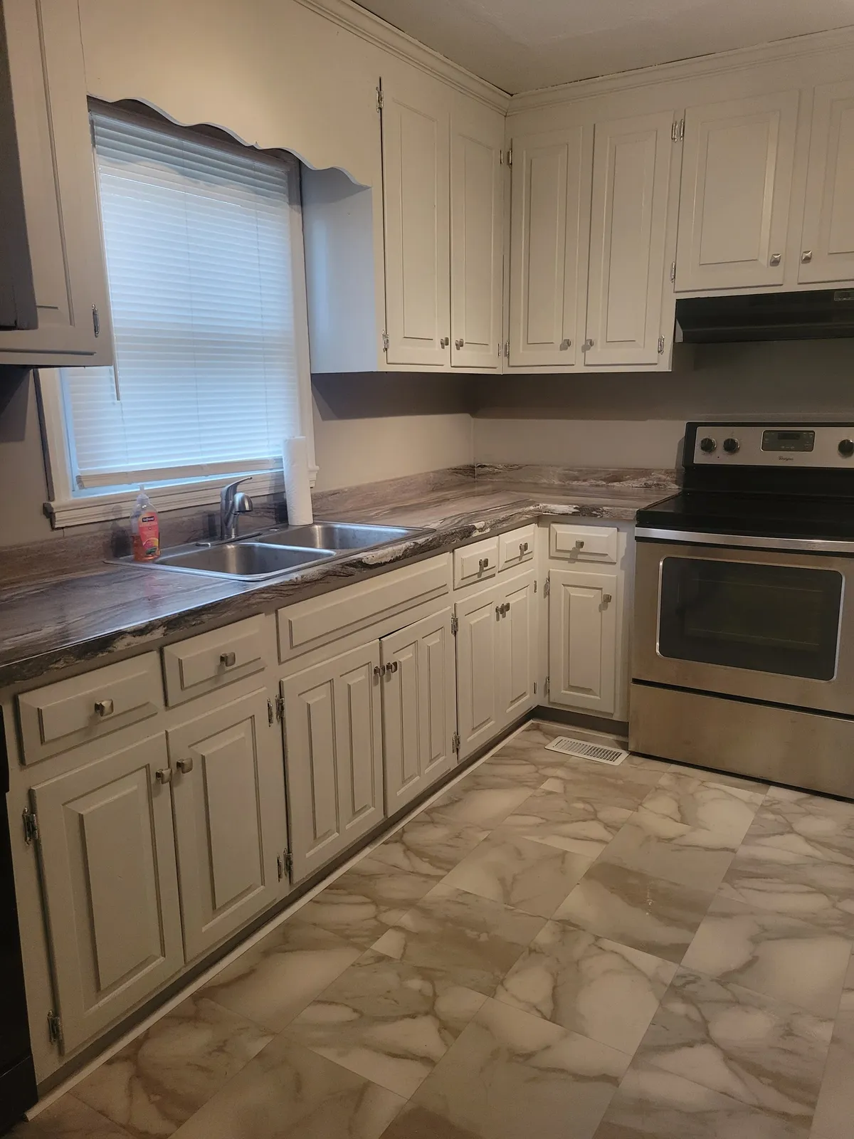 Kitchen with white cabinets, a stainless range and a patterned tile floor