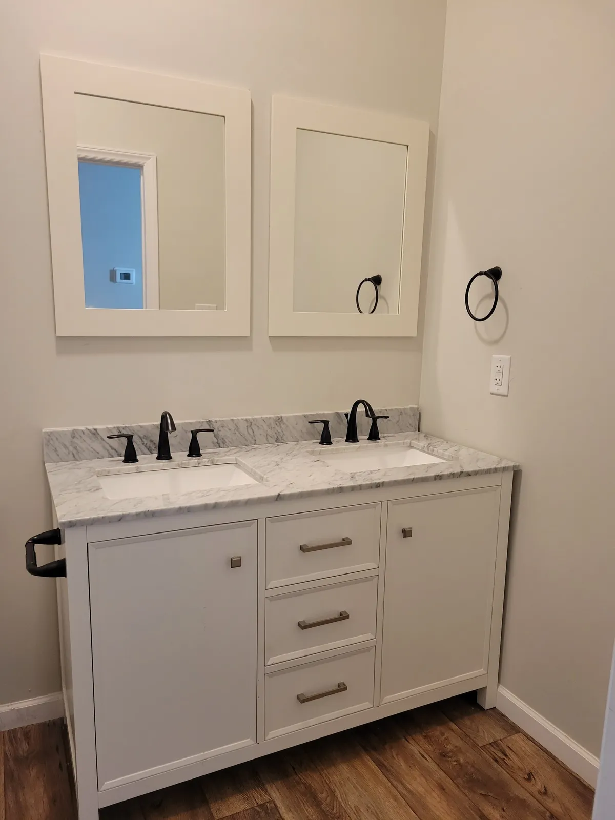 Bathroom with a white double vanity, black faucets and two white-framed mirrors