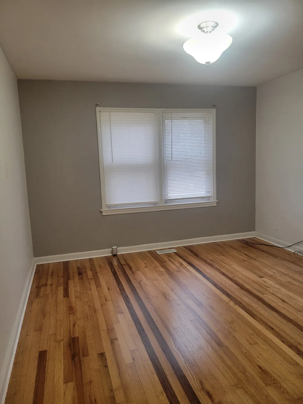 Empty room with a wood floor, dark accent stripes and a double window