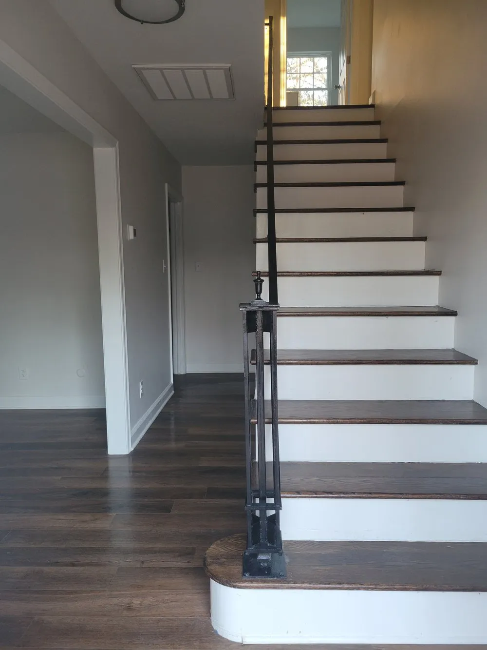 Wood staircase with white risers and a dark handrail